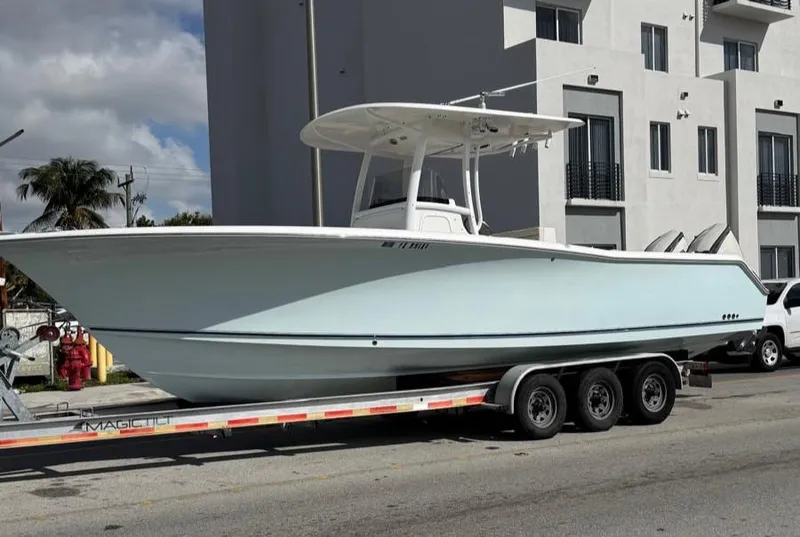 Slide: The Image of 2013 Sea Hunt Gamefish 29 boat on trailer, parked near modern building. - 1