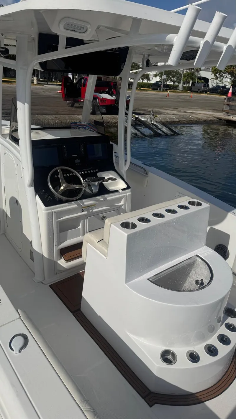 Slide: The Image of 2013 Sea Hunt Gamefish 29 boat interior with helm and seating, docked by the water. - 10
