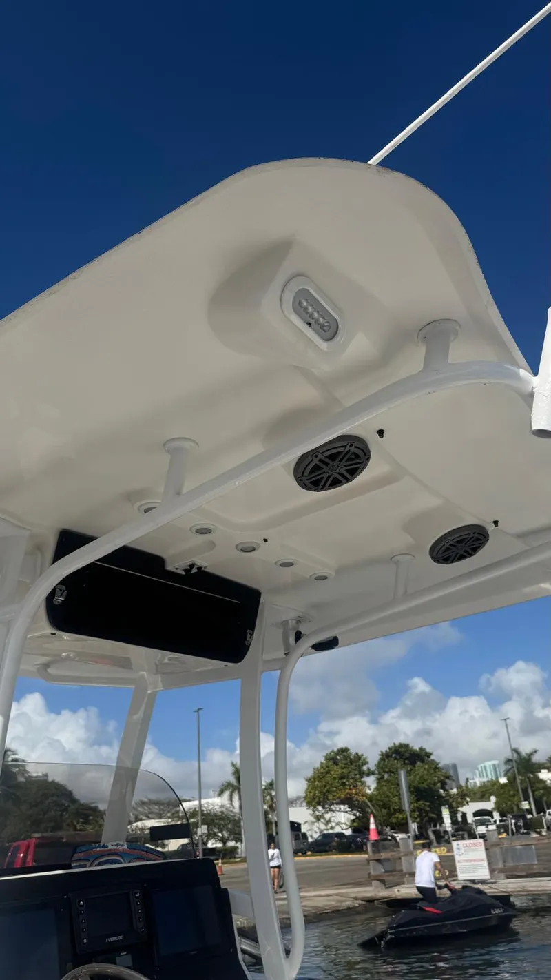 Slide: The Image of 2013 Sea Hunt Gamefish 29 boat with T-top and speakers, docked under clear blue sky. - 4