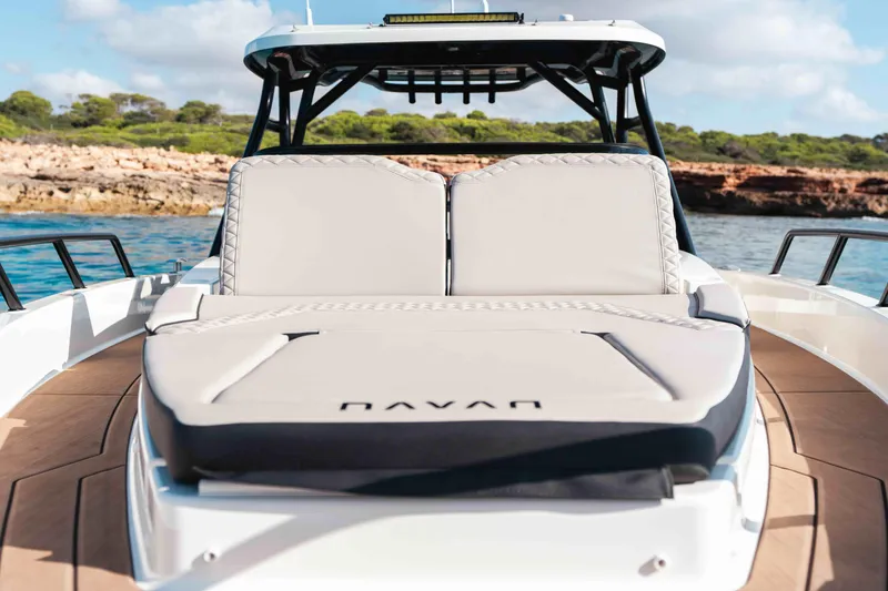 Slide: The Image of 2025 Navan S30 boat with cushioned seating, docked near rocky shoreline under blue sky. - 17