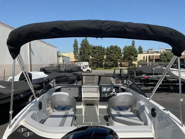Slide: The Image of 2025 Bayliner V20 boat with canopy, parked outdoors, showcasing interior seating and steering console. - 10