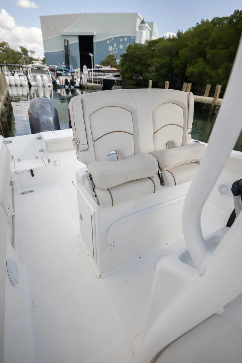 Slide: The Image of 2020 Sea Hunt GAMEFISH boat interior with cushioned seating, docked near a marina. - 12