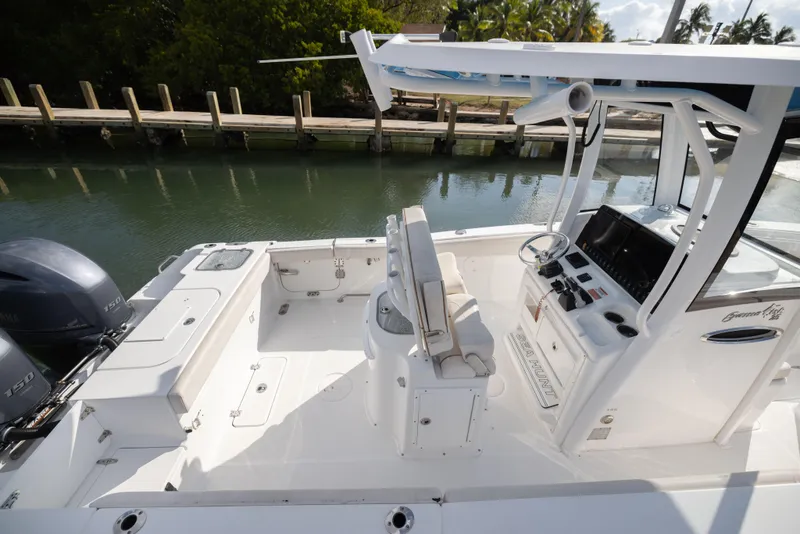 Slide: The Image of 2020 Sea Hunt GAMEFISH boat interior with dual engines, helm, and seating near a dock. - 13