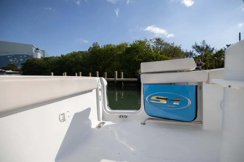 Slide: The Image of 2020 Sea Hunt GAMEFISH boat interior with logo, docked near lush greenery under blue sky. - 14