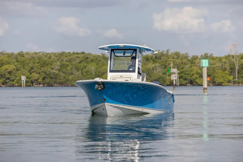 Slide: The Image of 2020 Sea Hunt GAMEFISH boat on calm water, surrounded by lush greenery. - 5