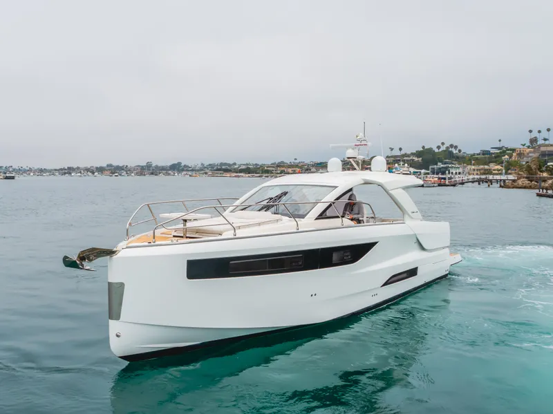 Slide: The Image of 2024 Jeanneau DB/43 OB yacht cruising on calm waters near a coastal town. - 4