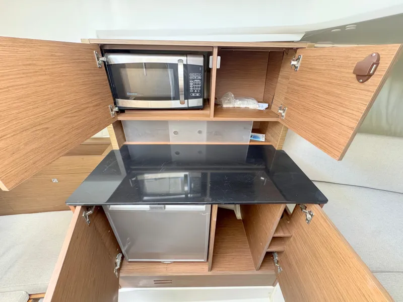Slide: The Image of Compact kitchen area in a 2018 Jeanneau Leader 9.0 WA boat with microwave and fridge. - 14