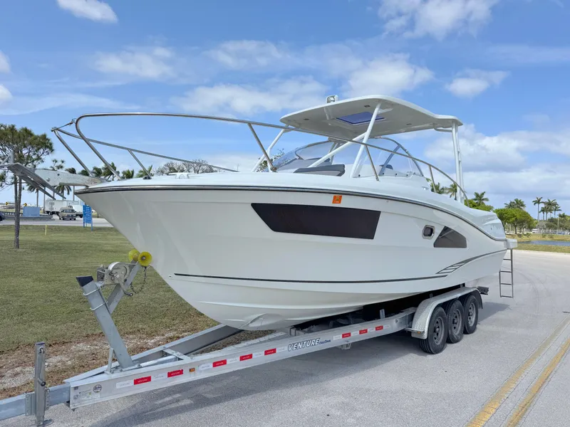 Slide: The Image of 2018 Jeanneau Leader 9.0 WA boat on trailer, parked outdoors under blue sky. - 2