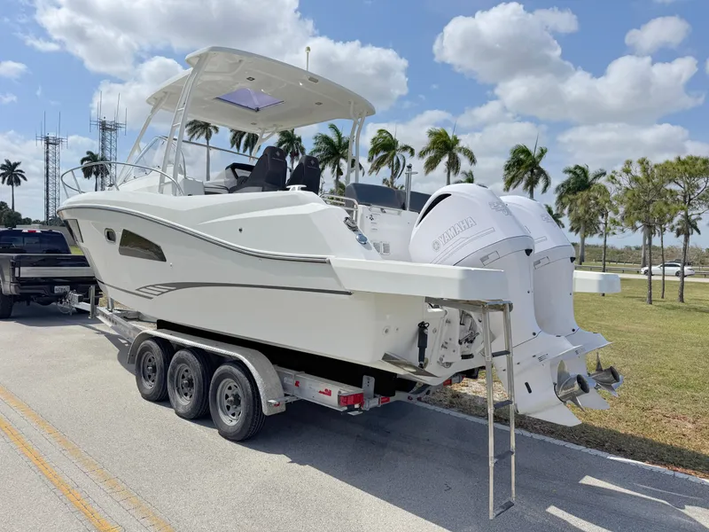 Slide: The Image of 2018 Jeanneau Leader 9.0 WA boat on trailer, parked roadside under a sunny sky. - 3