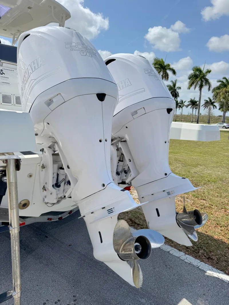 Slide: The Image of Twin outboard engines on a 2018 Jeanneau Leader 9.0 WA boat, parked near palm trees. - 38