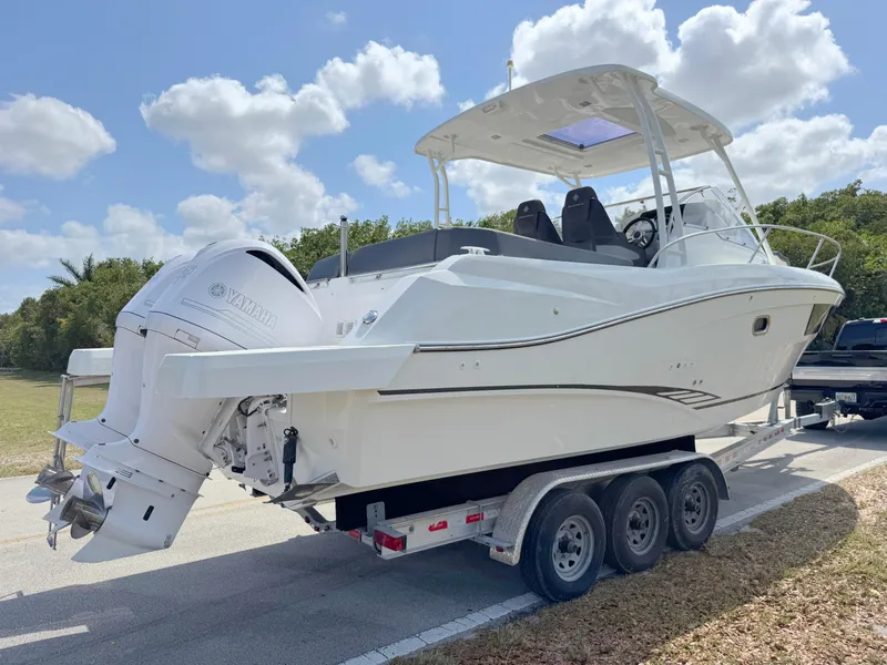 Slide: The Image of 2018 Jeanneau Leader 9.0 WA boat on trailer, parked outdoors under a blue sky. - 5