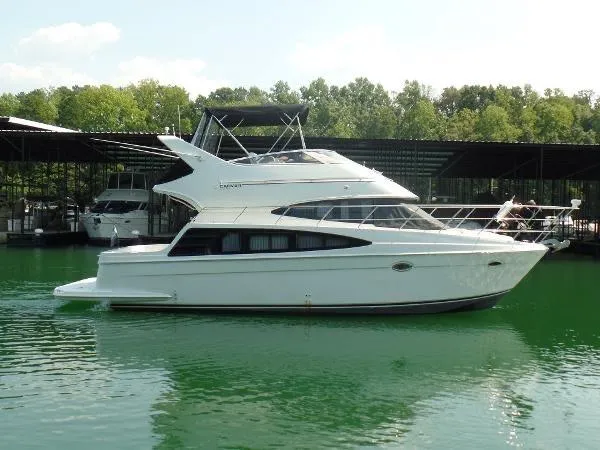 Slide: The Image of 2003 Carver 360 Sport Sedan yacht docked on calm water, surrounded by trees and covered slips. - 11