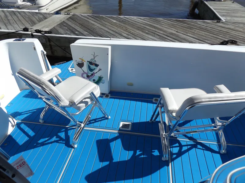 Slide: The Image of 2003 Carver 360 Sport Sedan boat deck with blue flooring and white chairs. - 14