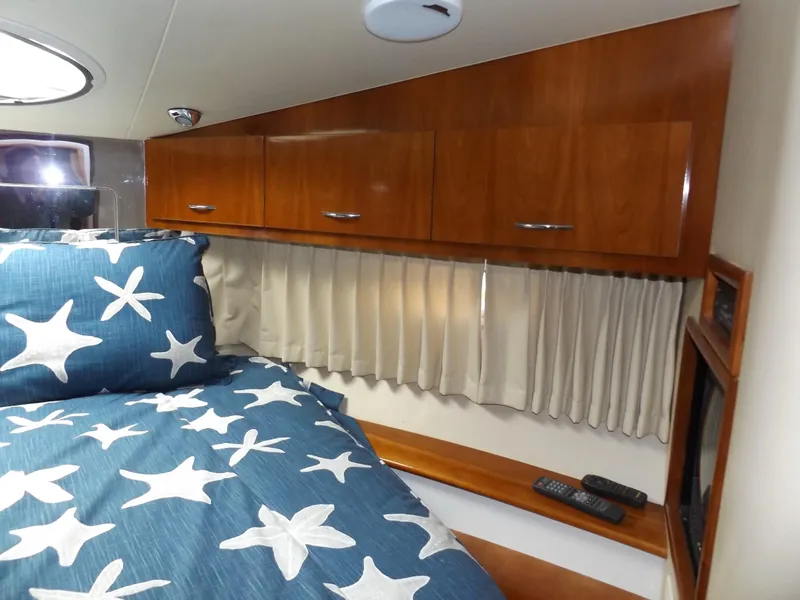 Slide: The Image of 2003 Carver 360 Sport Sedan cabin with starfish bedding and wooden cabinets. - 28