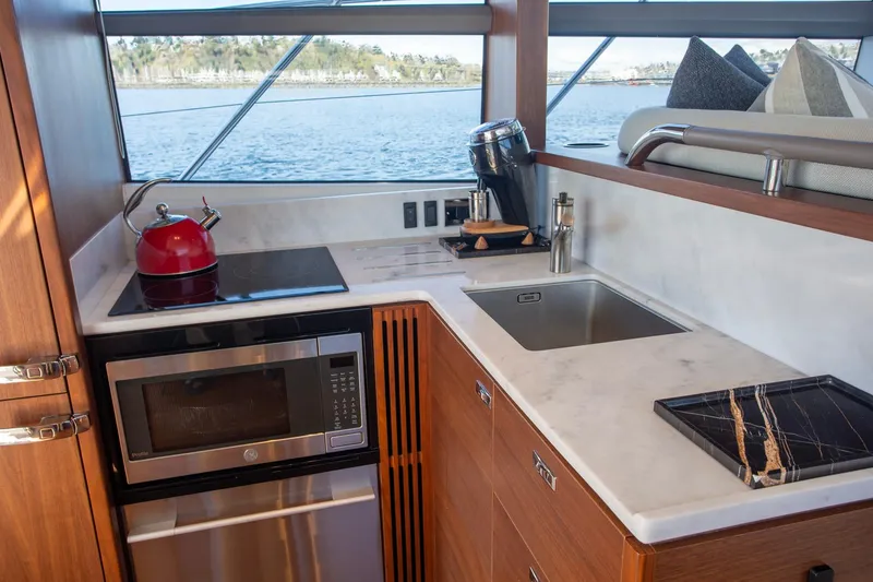 Slide: The Image of Modern yacht kitchen with appliances, featuring a red kettle and scenic ocean view. Princess F50, 2022. - 22