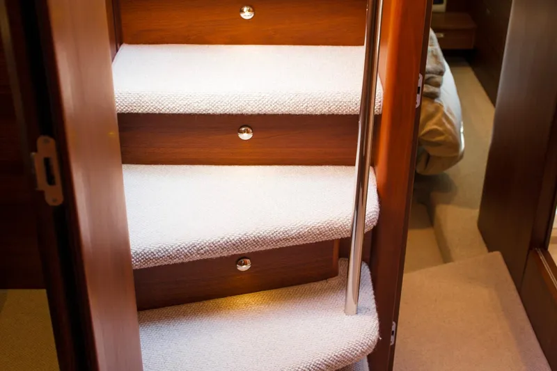 Slide: The Image of Carpeted stairs inside 2022 Princess F50 yacht, featuring wooden finish and metal handrail. - 35