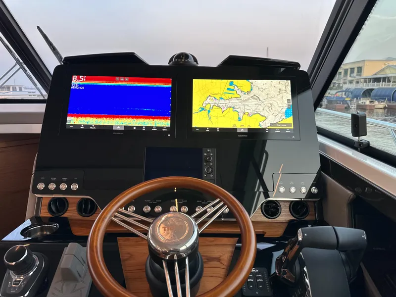 Slide: The Image of 2024 Tiara Yachts 48 LE helm with dual navigation screens and wooden steering wheel. - 10