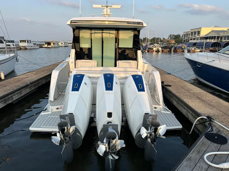 Slide: The Image of 2024 Tiara Yachts 48 LE with triple outboard engines docked at marina. - 2