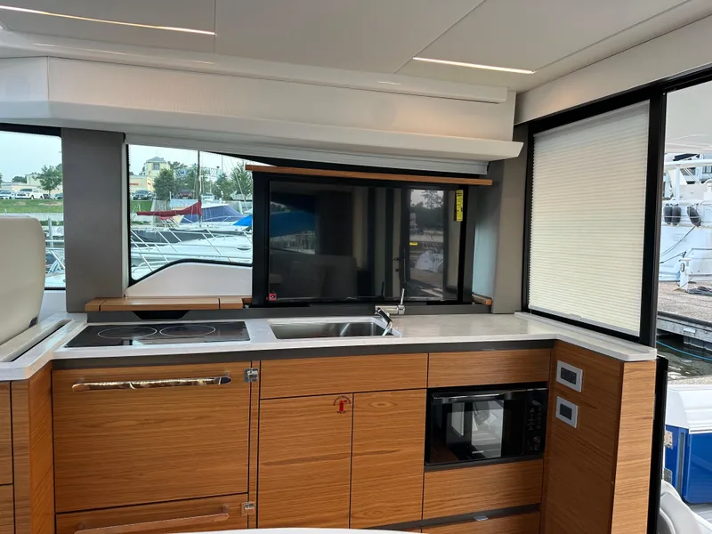 Slide: The Image of 2024 Tiara Yachts 48 LE interior kitchen with modern appliances and sleek wood cabinetry. - 7