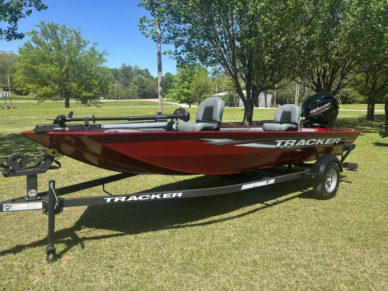 Slide: The Image of 2025 Tracker Panfish 17 boat on trailer, parked on grass with trees in background. - 5