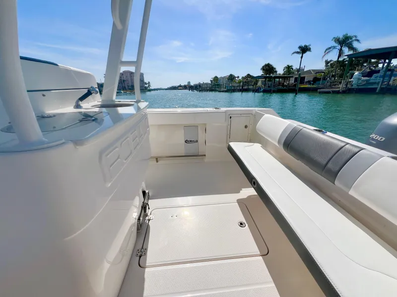 Slide: The Image of 2022 Robalo R272 Center Console boat interior with seating, overlooking a scenic waterfront. - 11