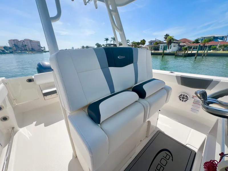 Slide: The Image of 2022 Robalo R272 Center Console boat interior with cushioned seating, overlooking waterfront homes. - 14