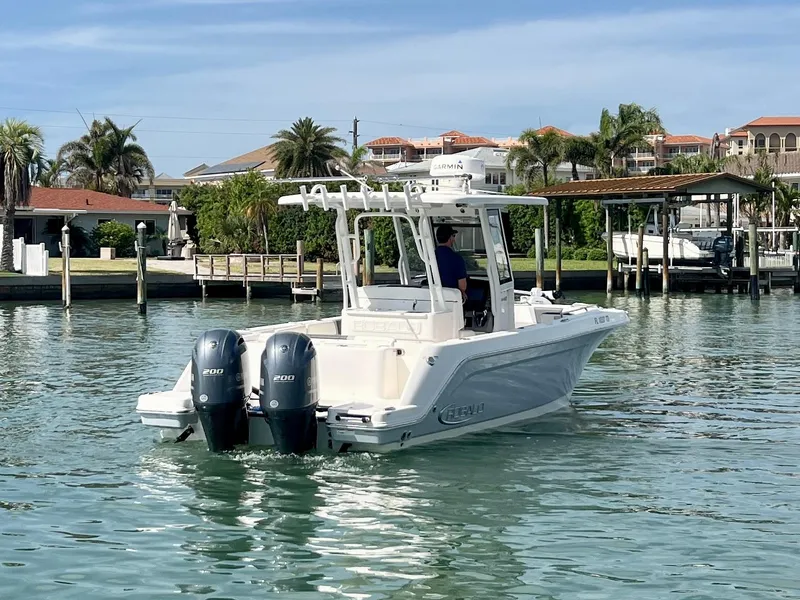 Slide: The Image of 2022 Robalo R272 Center Console boat cruising in a scenic waterfront area. - 2