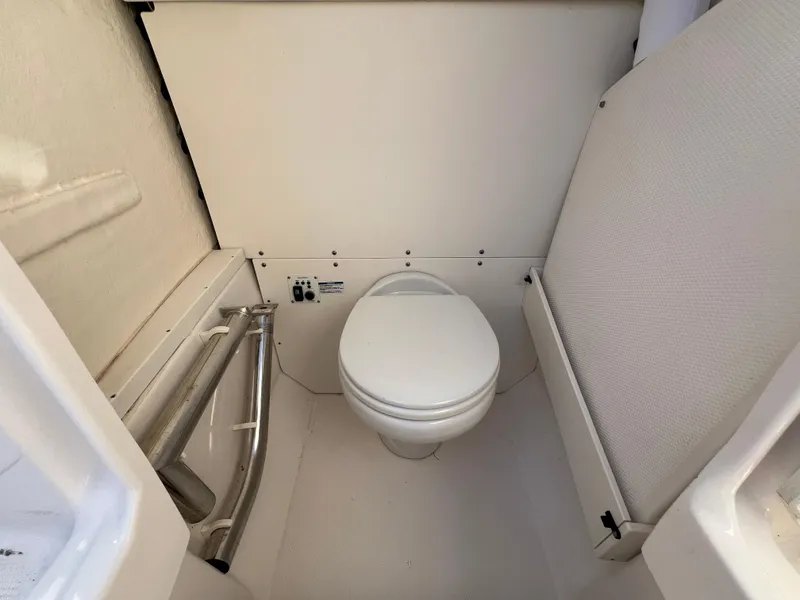 Slide: The Image of 2022 Robalo R272 Center Console boat interior with compact marine toilet. - 20