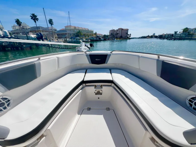 Slide: The Image of 2022 Robalo R272 Center Console boat with spacious seating, docked in a scenic marina. - 24