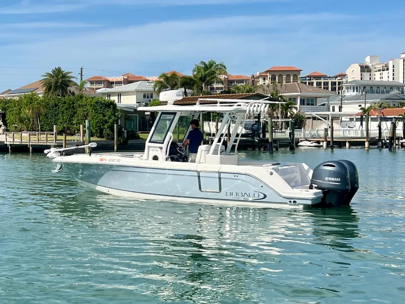 Slide: The Image of 2022 Robalo R272 Center Console boat on calm water near a marina. - 4