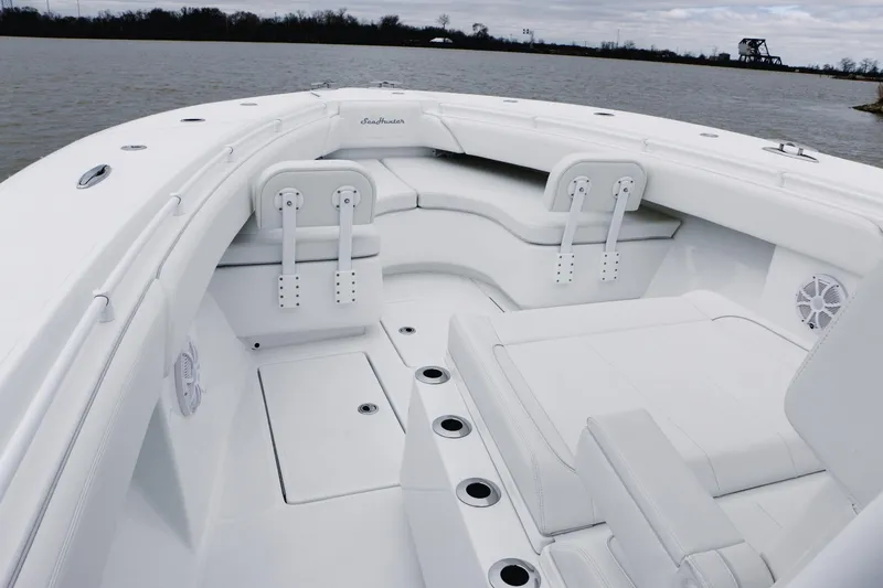 Slide: The Image of 2024 SeaHunter 35 Tournament boat interior with seating and rod holders on a calm lake. - 14