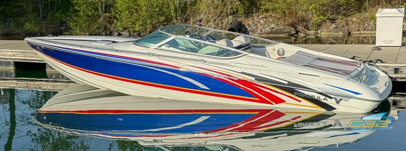 Slide: The Image of 2008 Formula 292 FASTech boat with vibrant red, blue, and white design docked on calm water. - 1