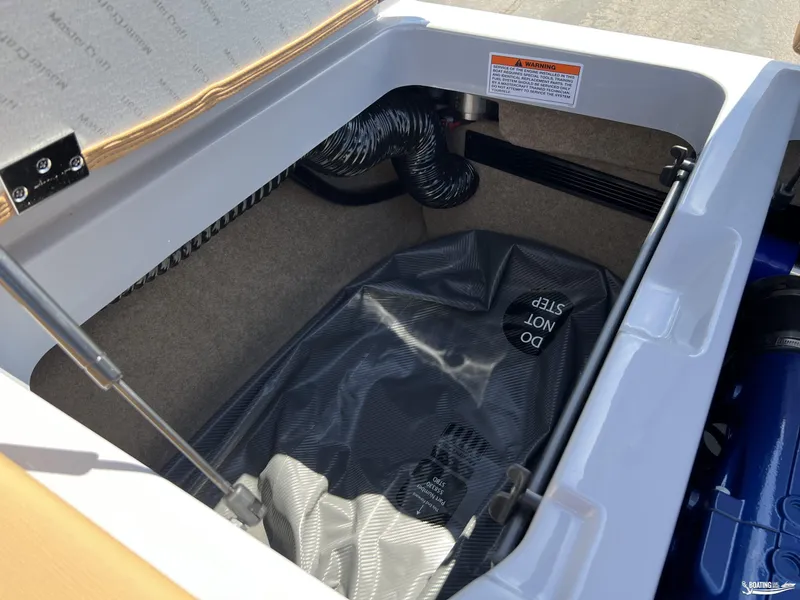 Slide: The Image of 2025 MasterCraft NXT24 storage compartment with warning label and protective cover. - 17