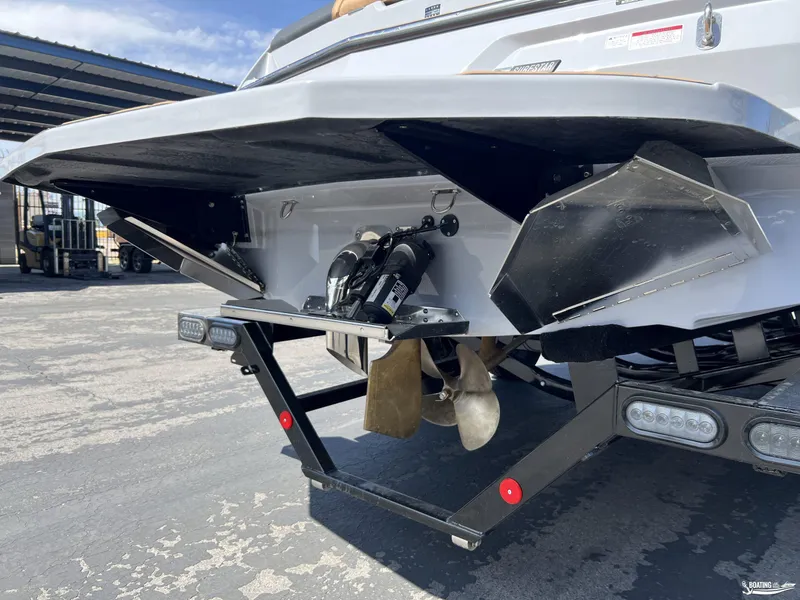 Slide: The Image of 2025 MasterCraft NXT24 boat stern with propeller and trim tabs in a parking area. - 18