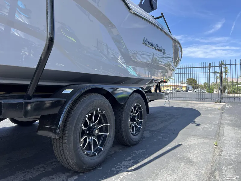 Slide: The Image of 2025 MasterCraft NXT24 boat on trailer, parked outdoors with clear sky. - 19
