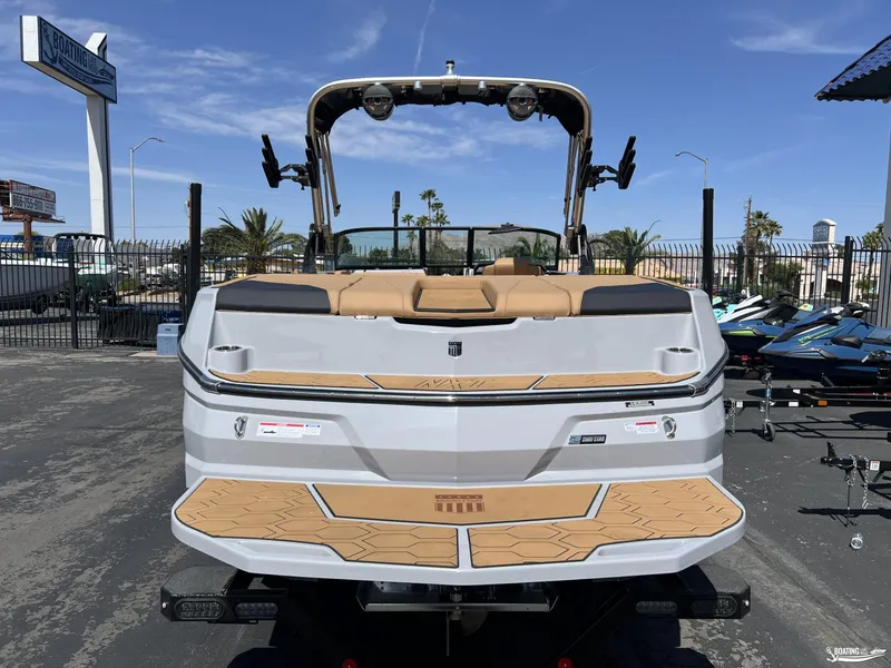 Slide: The Image of 2025 MasterCraft NXT24 boat, rear view, in a dealership lot under clear blue sky. - 3