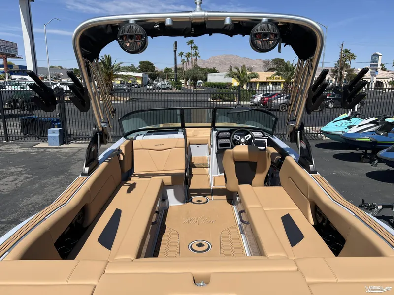 Slide: The Image of 2025 MasterCraft NXT24 boat interior with tan seating and modern dashboard, parked outdoors. - 4
