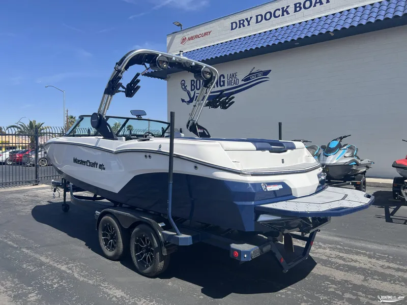 Slide: The Image of 2025 MasterCraft NXT22 boat on trailer at dealership, featuring sleek design and modern features. - 1