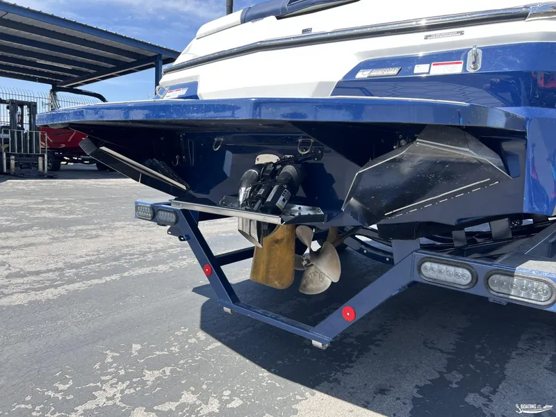 Slide: The Image of 2025 MasterCraft NXT22 boat stern with propeller and trailer, parked outdoors. - 18