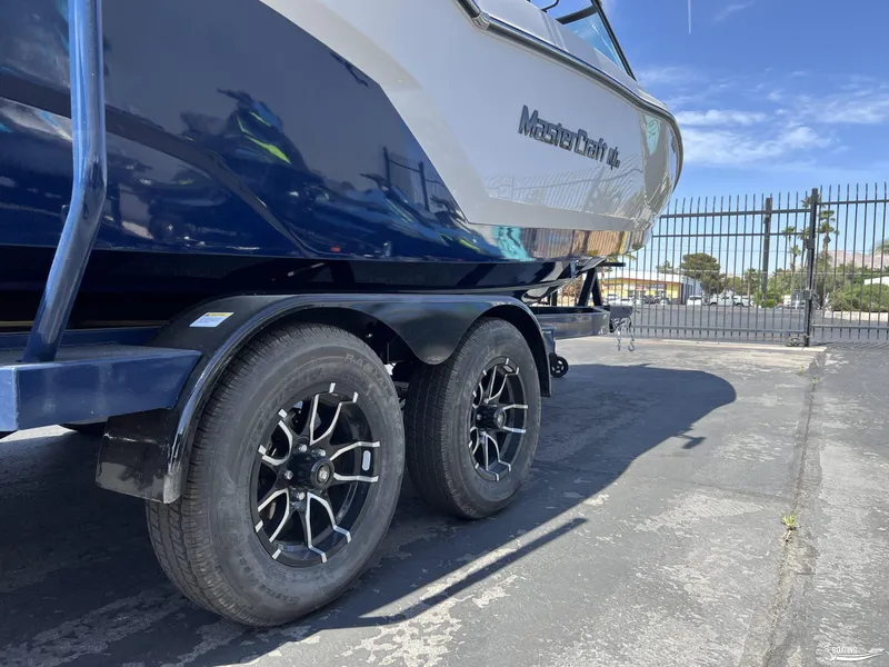Slide: The Image of 2025 MasterCraft NXT22 boat on trailer, showcasing sleek design and modern wheels. - 19