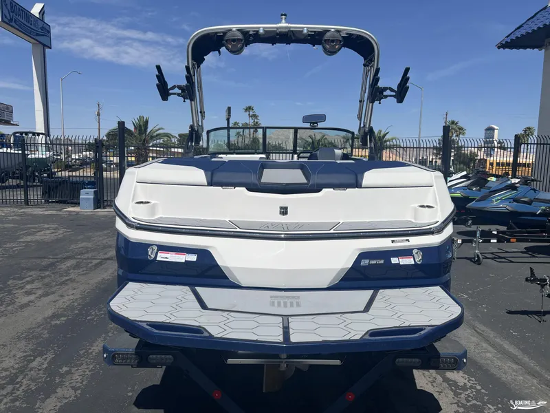 Slide: The Image of 2025 MasterCraft NXT22 boat, rear view, in a dealership lot under clear skies. - 3