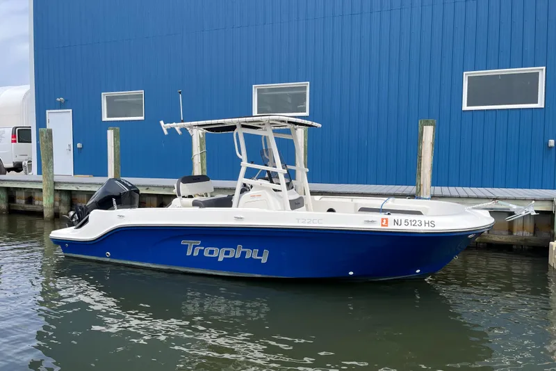 Slide: The Image of 2023 Bayliner Trophy T22CC boat docked by a blue building. - 0