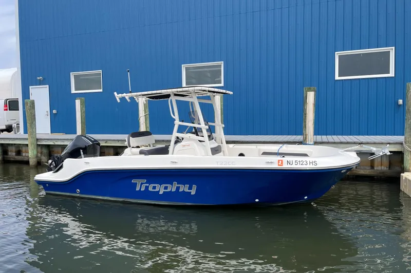 Slide: The Image of 2023 Bayliner Trophy T22CC boat docked by a blue building. - 10