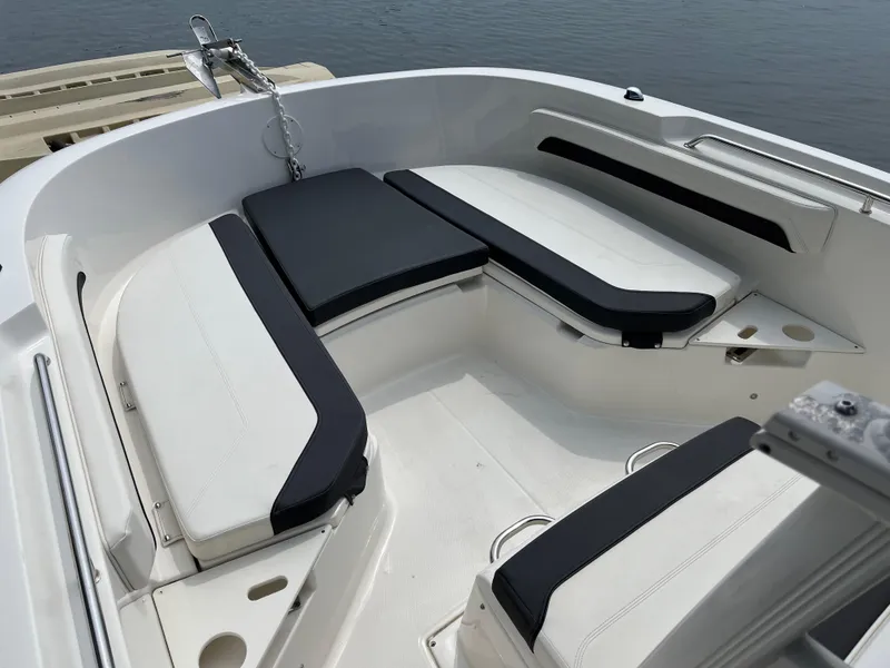 Slide: The Image of 2023 Bayliner Trophy T22CC boat interior with cushioned seating and anchor, docked by the water. - 4