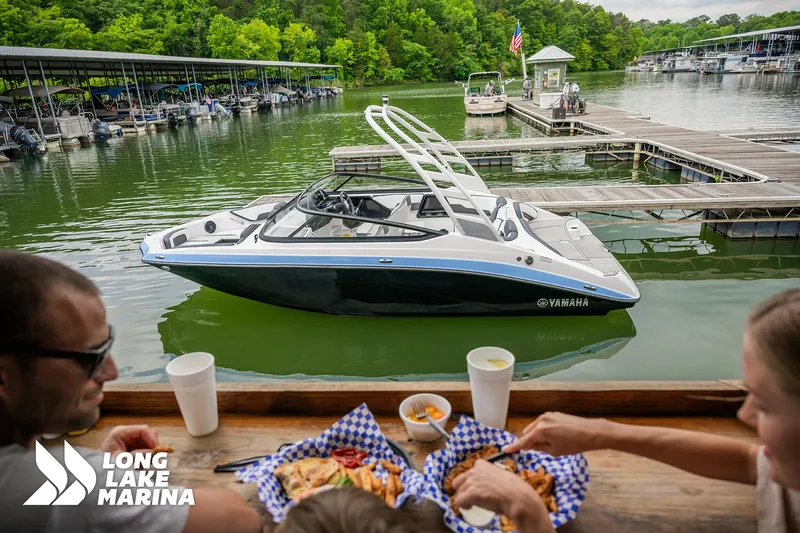 Slide: The Image of 2025 Yamaha Boats 195S docked at Long Lake Marina, with people dining nearby. - 6