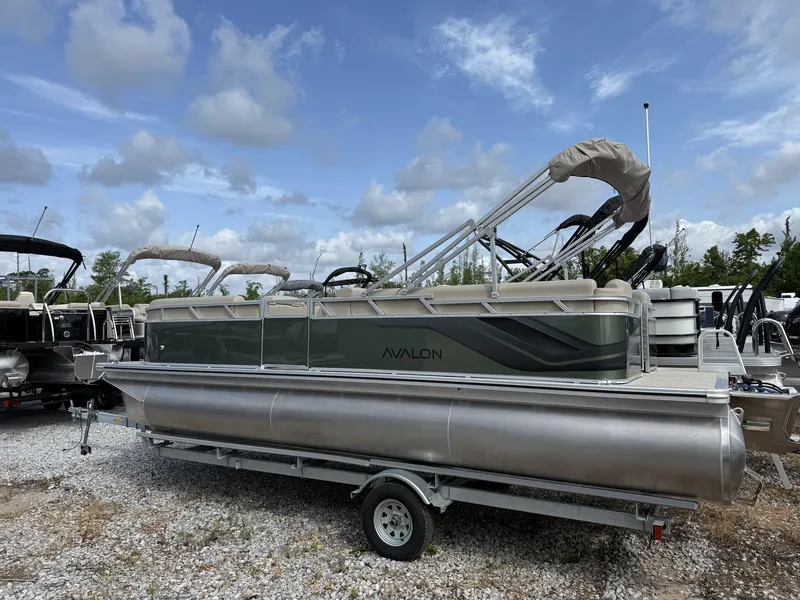 Slide: The Image of 2025 Avalon VLS 23 Quad Lounger pontoon boat on trailer under a blue sky. - 2