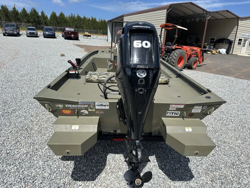Slide: The Image of 2024 Tracker Grizzly 1860 CC boat with Mercury 60 engine, parked on gravel. - 10