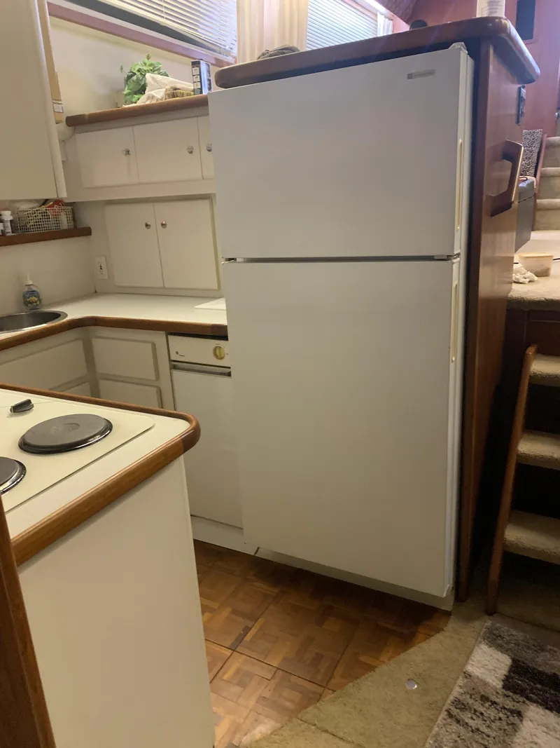 Slide: The Image of 1994 Carver 440 Aft Cabin Motor Yacht kitchen with white appliances and wood accents. - 32