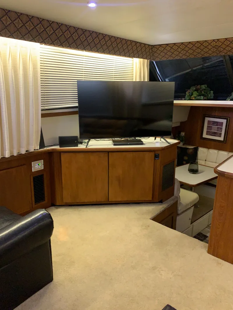 Slide: The Image of 1994 Carver 440 Aft Cabin Motor Yacht interior with TV and wooden cabinetry. - 44