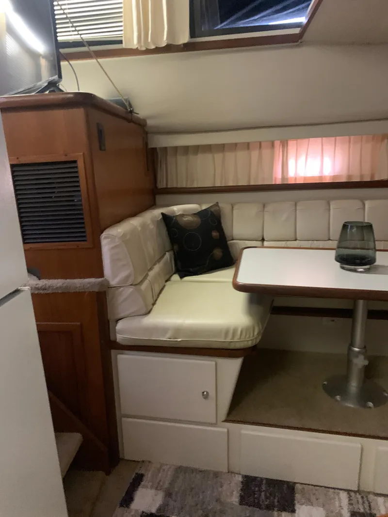 Slide: The Image of 1994 Carver 440 Aft Cabin Motor Yacht interior with dining area and cushioned seating. - 64